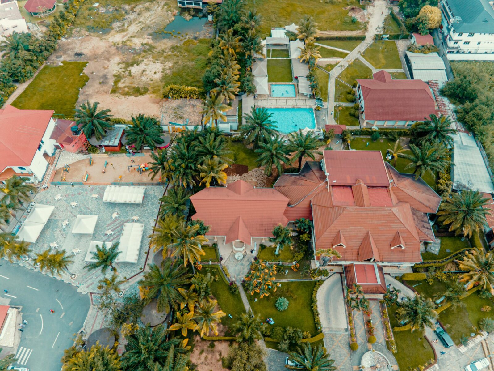 A stunning aerial view showcasing a luxurious resort with vibrant palm trees and a tranquil swimming pool.